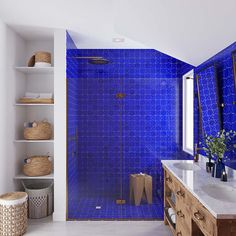 a bathroom with blue tiles on the walls and floor, along with a large mirror