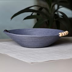 a blue bowl sitting on top of a table next to a green potted plant