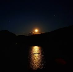 the moon shines brightly in the night sky over water