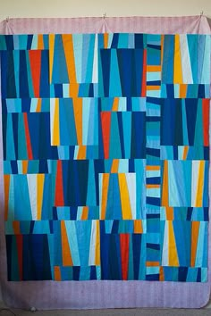 a blue and orange quilt hanging on a wall