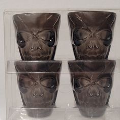 four shot glasses with skulls on them in a display case