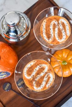 two desserts are sitting on a wooden tray with silverware and an orange pumpkin