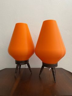 two orange lamps sitting on top of a wooden table