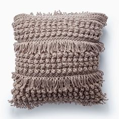 a crocheted pillow with fringes on the front and back, sitting on a white surface