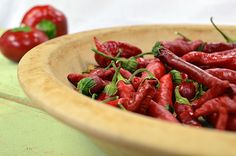 a wooden bowl filled with red hot peppers