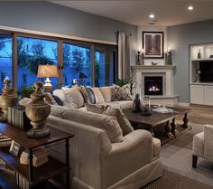 a living room filled with furniture and a fire place in front of a window covered in windows