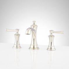 three silver faucets sitting on top of a white counter next to each other