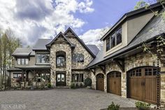 a large stone house with two garages on the front and one car in the driveway