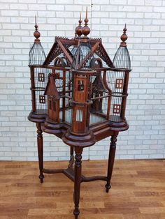 an ornate birdcage is on display in front of a brick wall and wooden floor