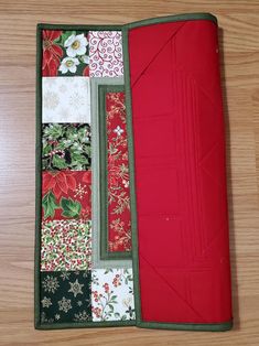 the inside of a red and green quilted case on a wooden table with flowers