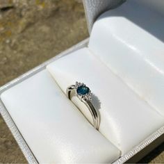 an engagement ring with a blue stone in a white box on top of a table