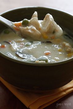 a green bowl filled with soup sitting on top of a wooden table next to a napkin