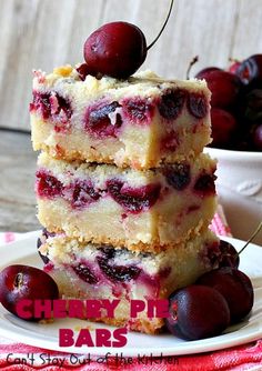 three pieces of cherry pie bars stacked on top of each other with cherries in the background