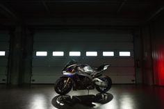 a motorcycle is parked in a garage with red light coming from the ceiling and it's shadow on the floor