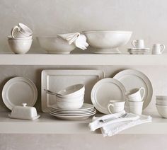 white dishes and cups are stacked on a shelf