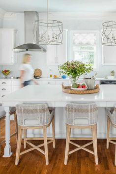 a kitchen with two chairs and a table in front of the counter top that has fruit on it