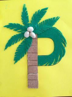 a palm tree made out of construction paper on a piece of yellow paper that is cut into the shape of a letter d