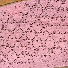 a pink crocheted blanket sitting on top of a brick wall