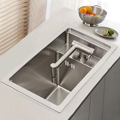 a stainless steel sink in a kitchen with fruit on the counter top and window blinds