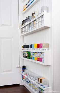 a white wall with shelves filled with paint and supplies