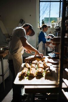 a man preparing food on top of a wooden cutting board