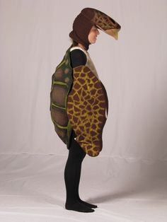 a woman wearing a turtle costume standing in front of a white backdrop with her back turned to the camera