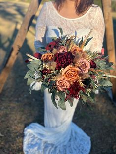 a woman holding a bridal bouquet in her hands and posing for the camera outside