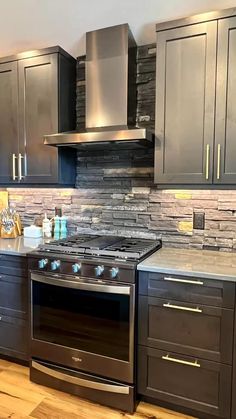 a stove top oven sitting inside of a kitchen next to wooden floors and gray cabinets