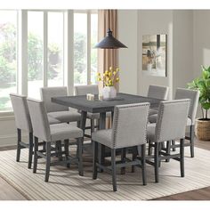 a dining room table with grey chairs and a lamp on the wall next to it