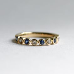 a yellow gold ring with blue and white stones on the side, sitting on a plain surface