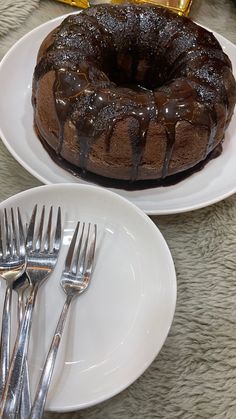 a chocolate bundt cake sitting on top of a white plate next to silverware