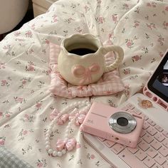 a laptop computer sitting on top of a bed next to a pink flowered blanket