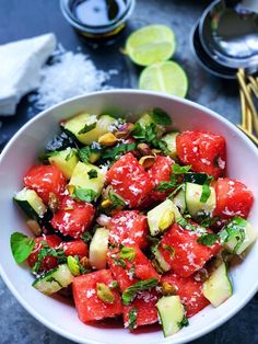 a white bowl filled with watermelon and cucumber salad on top of a table