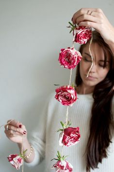 a woman is holding flowers in front of her face and looking down at the stems