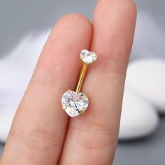 a person's hand holding a gold nose ring with two diamonds on the side