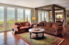 a living room filled with furniture and large windows overlooking the ocean on a sunny day