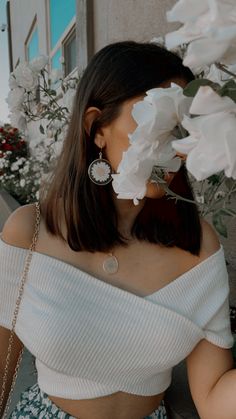 a woman with flowers in her hair wearing a white top and blue floral print skirt