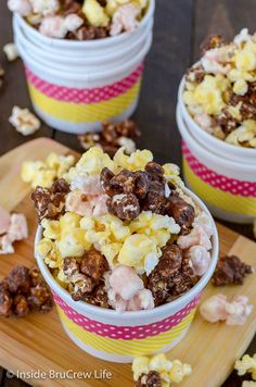 three bowls filled with popcorn on top of a wooden cutting board