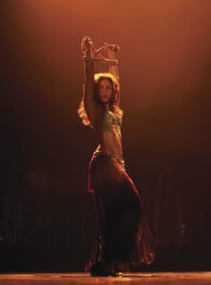 a belly dancer is performing on stage with her arms in the air and headdress