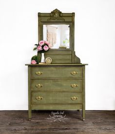 a green dresser with flowers and a mirror on top