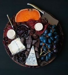 an assortment of cheeses and grapes on a plate