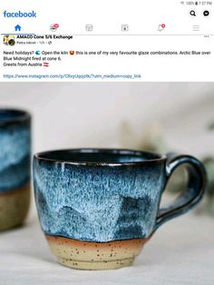 two coffee mugs sitting next to each other on top of a white tablecloth