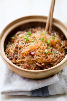 a wooden bowl filled with noodles and chopsticks on top of a white napkin