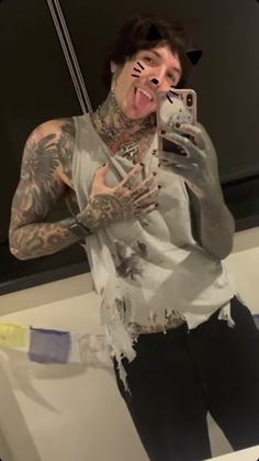 a man with tattoos taking a selfie in front of a mirror while holding a cell phone