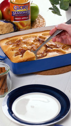 a person cutting into a baked apple pie on top of a white table with blue plates