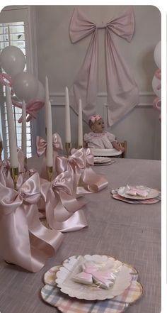 the table is set with pink and white plates, candles, and napkins on it