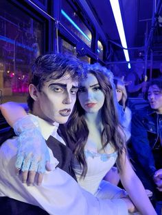 two people dressed in costumes posing for a photo together on a bus at night time