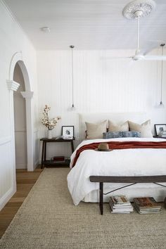 a bedroom with white walls and wood flooring has a large bed in the center