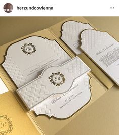 two white and gold wedding cards on top of each other