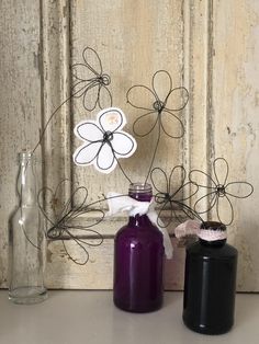 two vases with flowers in them sitting on a table next to an empty bottle